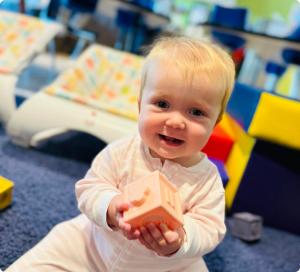Infant exploring a block during playtime at Ardent Preschool & Daycare, supporting early motor skills and sensory development